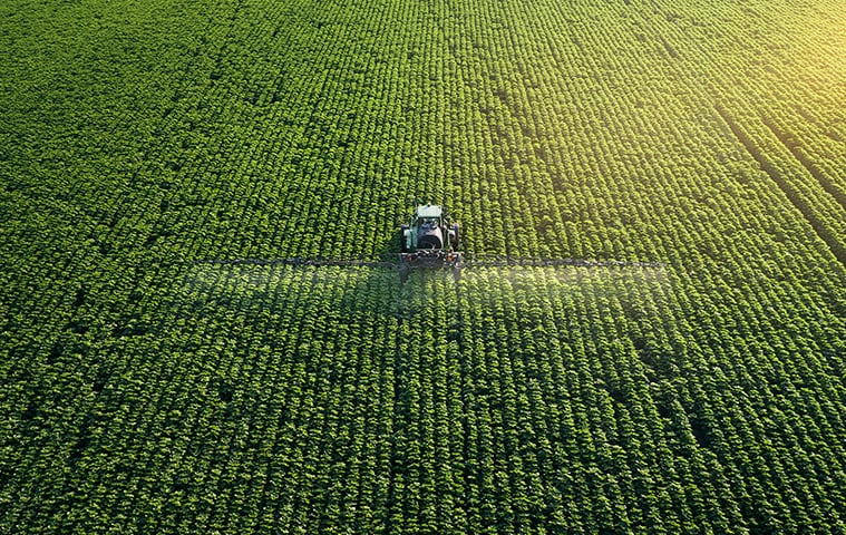 view from above a field of crops with a tractor in the middle of the field